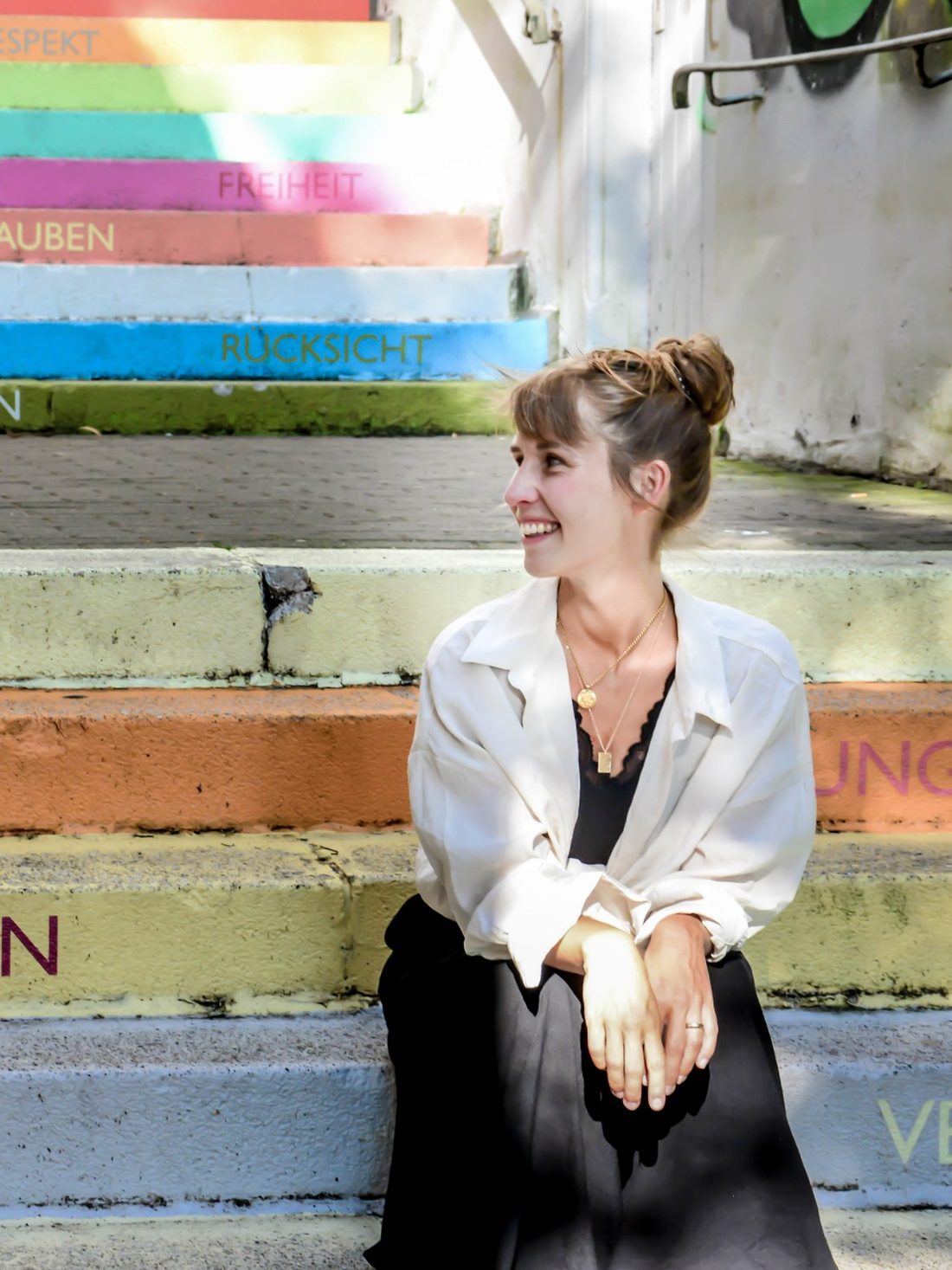 Alexandra de Carvalho sitting on a colourfully painted staircase in Wuppertal